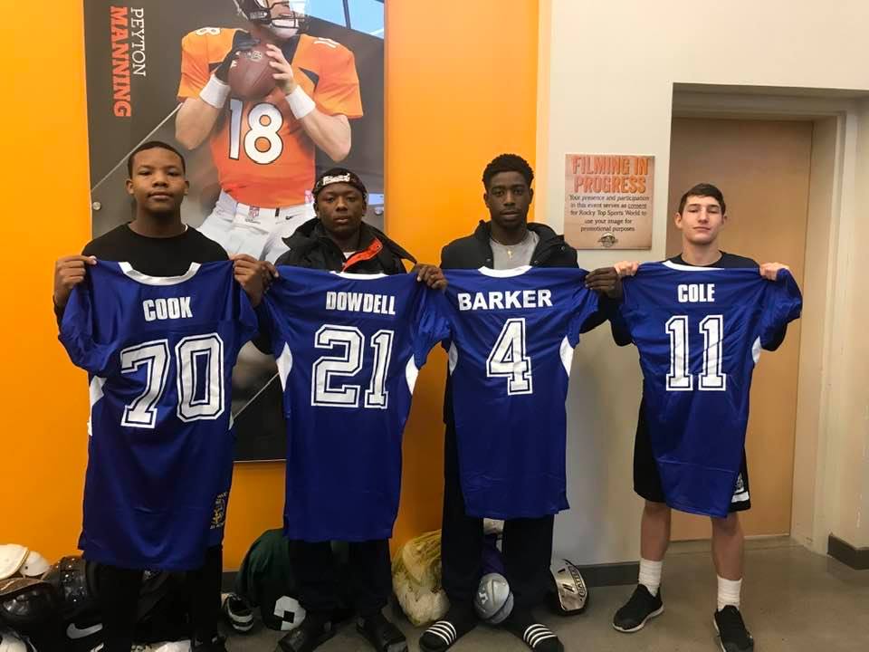 four cadets holding sports jerseys