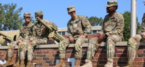 4 Cadets of Southern Prep Academy sit smiling, laughing, and talking on a brick wall.